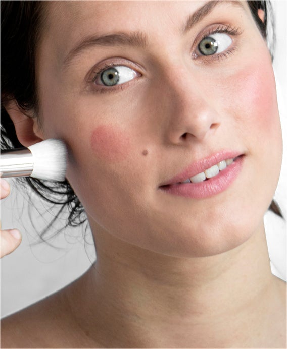 multi purpose facial brush for powders, foundations and other makeup applications to face. Woman applying makeup with brush to her face